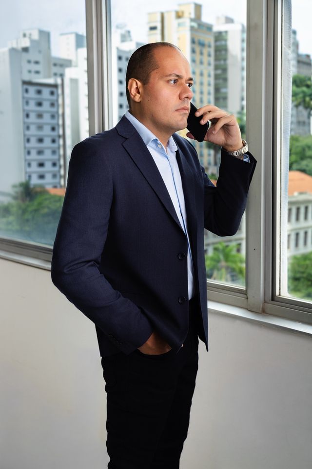 Matheus Marques em ligação, de pé junto à janela